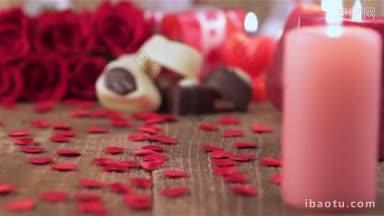 为情人节的爱情和浪漫的概念，红玫瑰和巧克力糖果与蜡烛在木头上